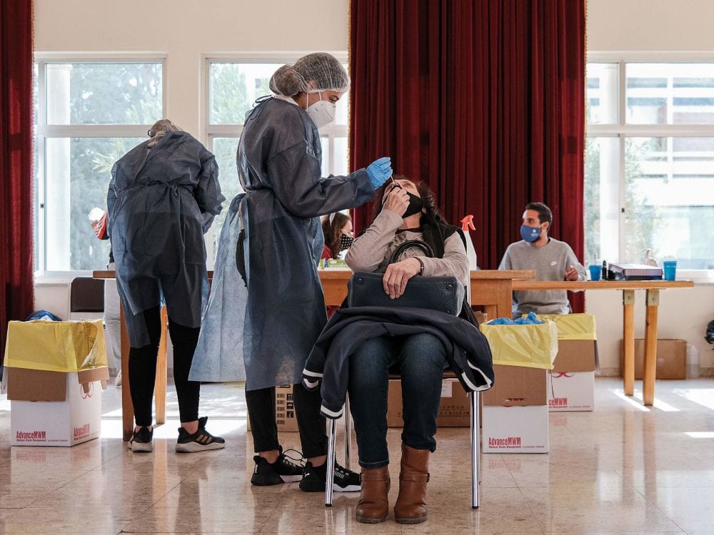 A medical worker performs a COVID-19 swab test upon a woman at a rapid-testing station at the Panagia Evangelistria Greek Orthodox Church in Cyprus' capital Nicosia on Jan. 29. PHOTO BY AMIR MAKAR/AFP