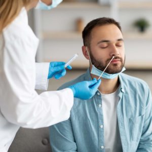 man getting nose swabbed by a nurse for an influenza test