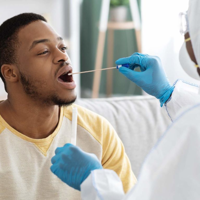un homme se fait tamponner la gorge par une infirmière pour un test Strep A