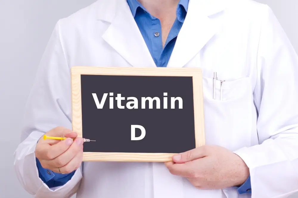 man in white doctor coat holding a chalkboard with Vitamin D written on it