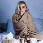 sick woman in bed with thermometer