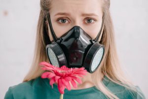 Blonde woman with pollen allergy wearing respirator mask