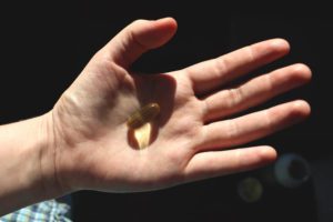 Vitamin D or omega 3 capsules. Vitamin gel in hand against the window. The concept of a lack of vitamin D in the body