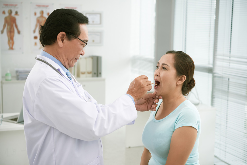 Doctor checking on matured woman's throat
