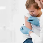 Child receiving vaccination from healthcare worker.